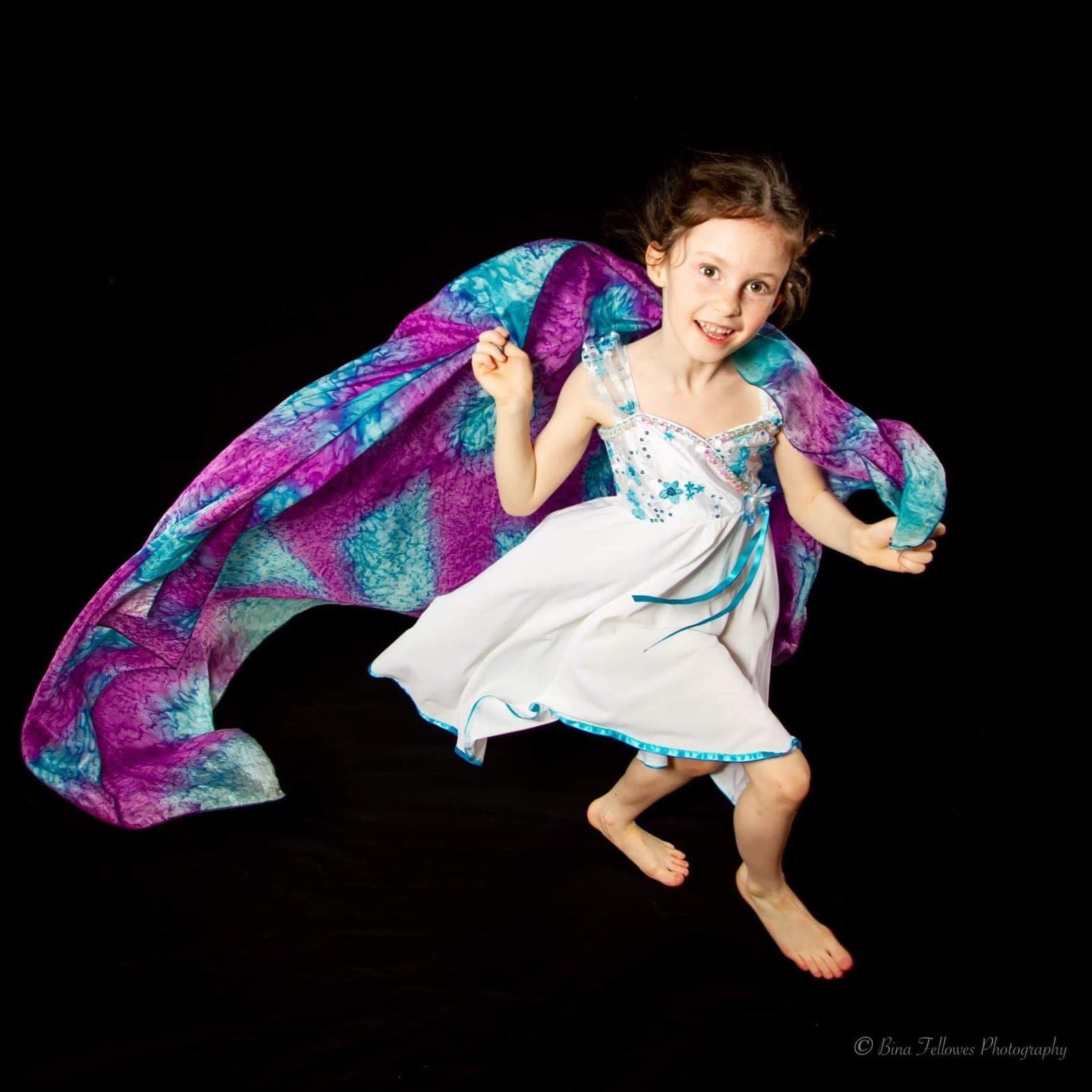 Young dancer leaping with a silk scarf