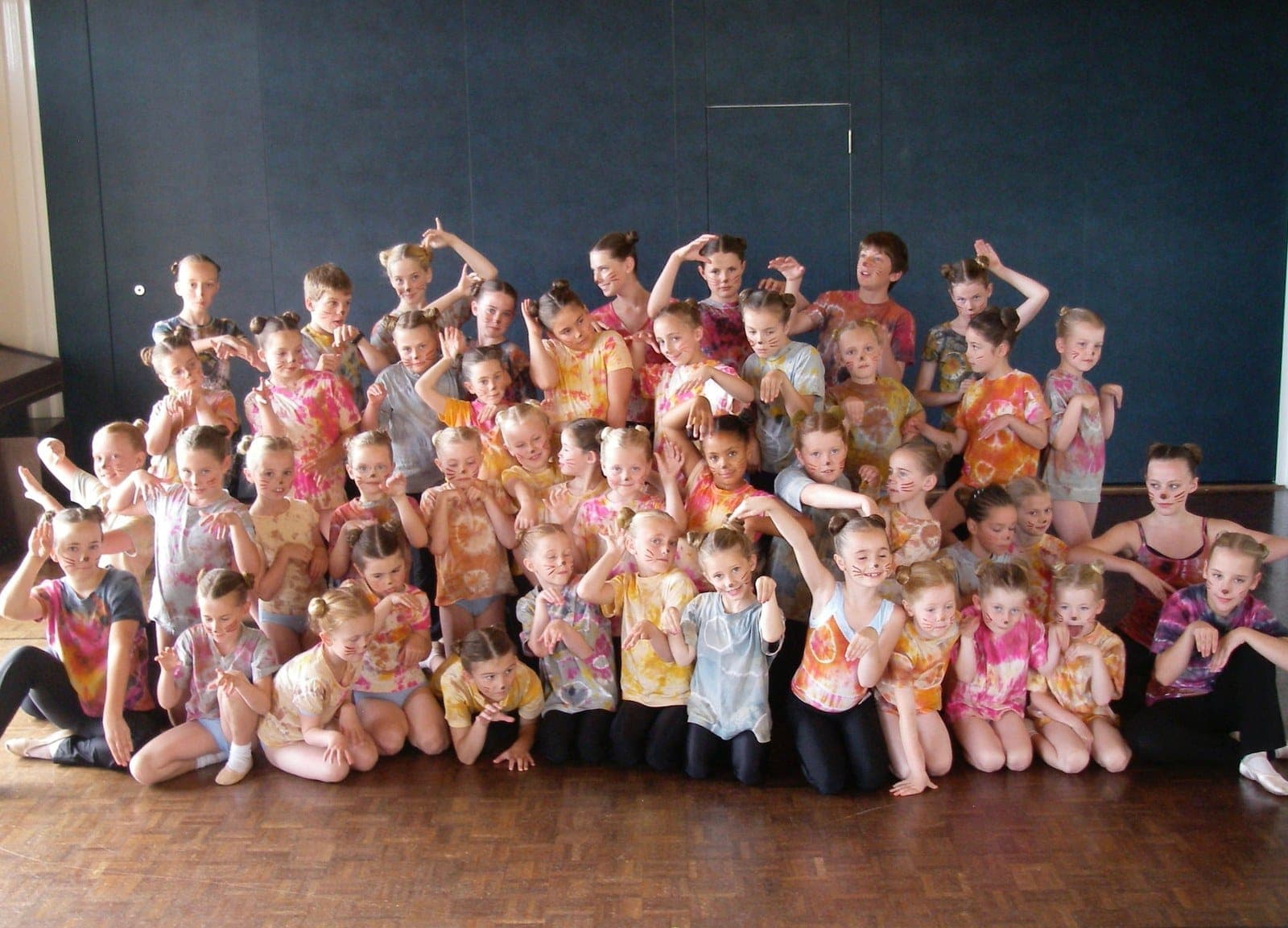 Full show cast in colourful costumes posing together